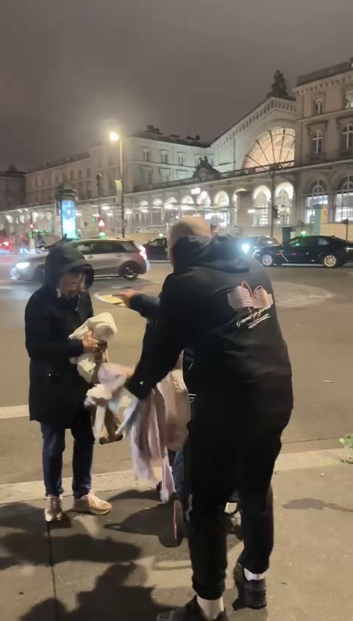 Un bénévole remet des vêtements à une personne lors d’une maraude.