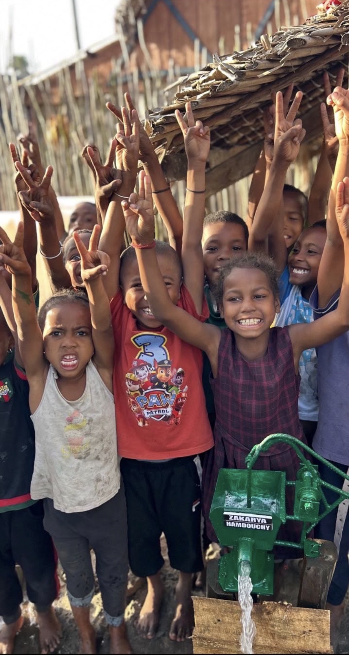 Des enfants réunis autour d’une pompe à eau portant le nom de Zakarya.